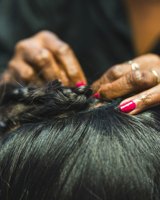 Close-up of hands working through hair, applying a hair care product at the root